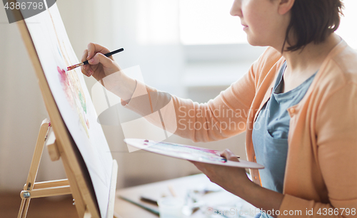 Image of artist with palette and brush painting at studio