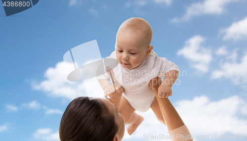 Image of happy mother playing with little baby boy over sky