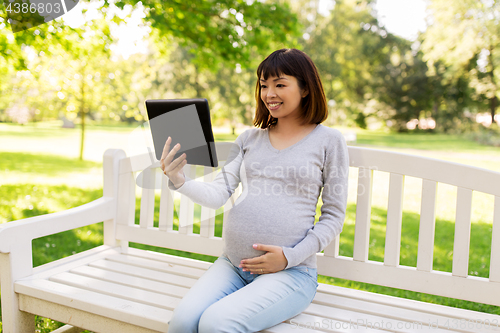 Image of happy pregnant asian woman with tablet pc at park