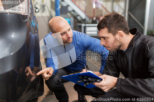 Image of auto mechanic and customer looking at car