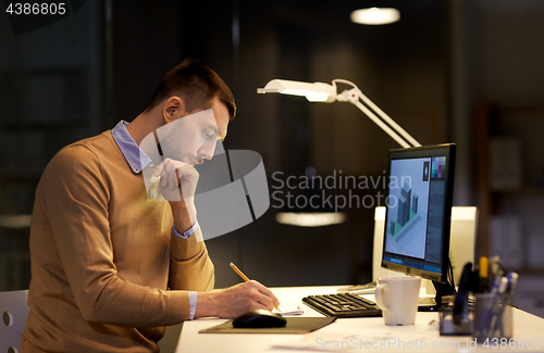 Image of man with notepad working at night office