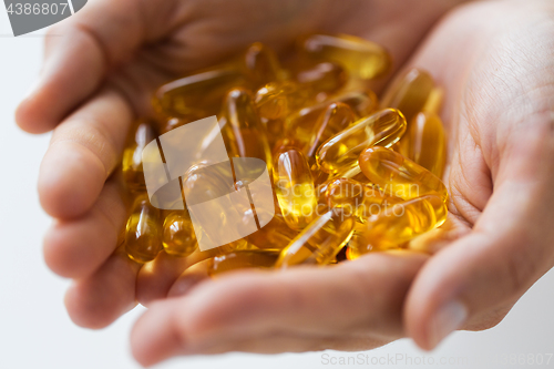 Image of hands holding cod liver oil capsules