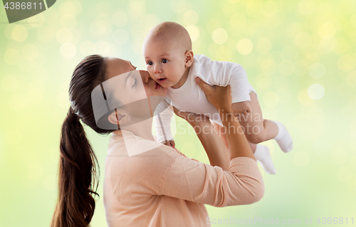 Image of happy mother kissing little baby boy over green