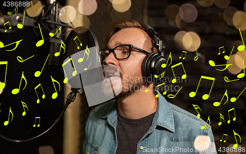 Image of man with headphones singing at recording studio