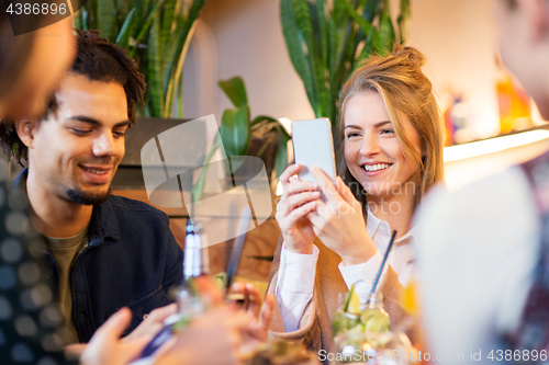 Image of friends with smartphones eating at restaurant