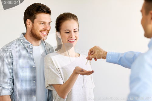 Image of realtor giving keys from new home to happy couple