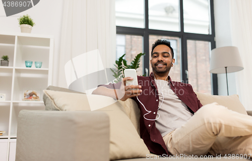 Image of man in earphones listening to music on smartphone