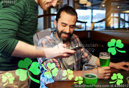 Image of friends with smartphone drinking green beer at pub