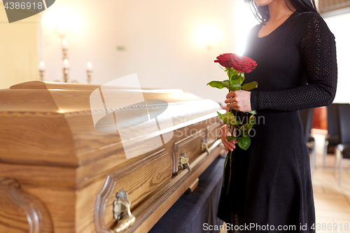 Image of woman with red roses and coffin at funeral