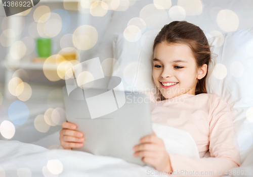 Image of happy girl in bed with tablet pc over lights