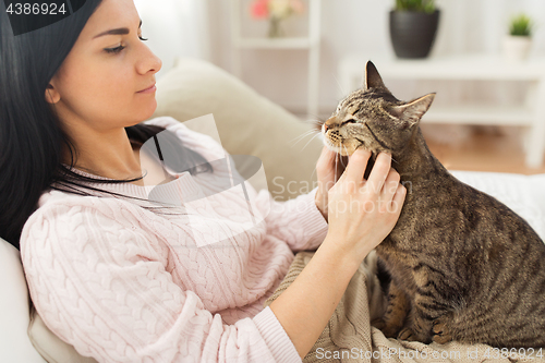 Image of close up of woman with tabby cat in bed at home