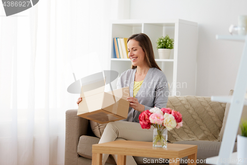 Image of smiling woman opening parcel box at home