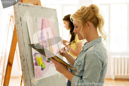 Image of woman with easel painting at art school studio