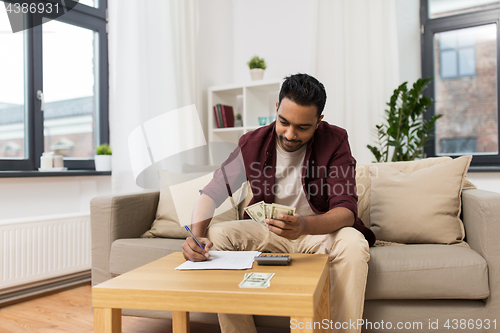 Image of man with money and calculator filling papers