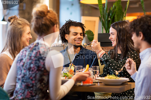 Image of happy friends eating at restaurant