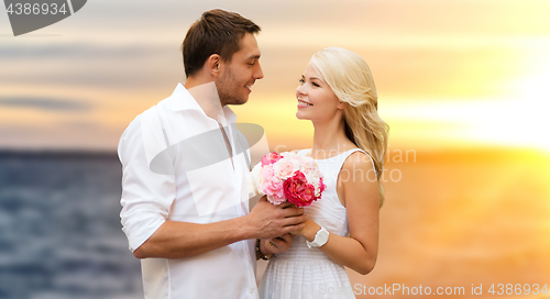 Image of happy couple with flowers over sea background