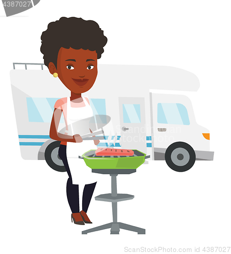 Image of Woman having barbecue in front of camper van.