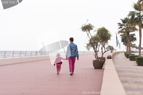 Image of mother and cute little girl on the promenade by the sea