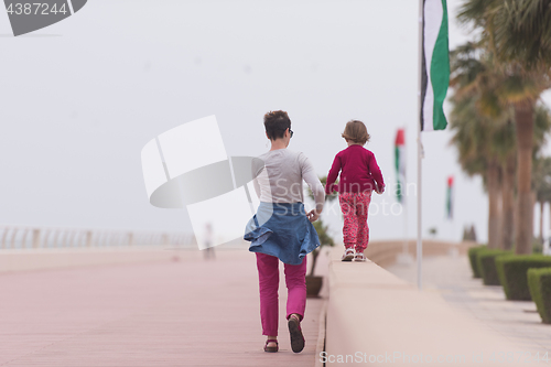 Image of mother and cute little girl on the promenade by the sea