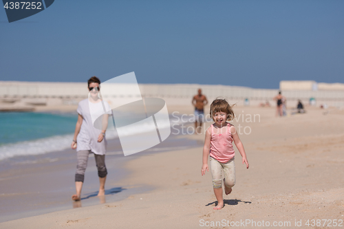 Image of mother and daughter running on the beach