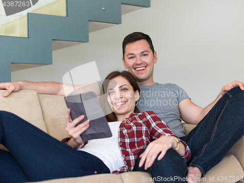 Image of couple relaxing at  home with tablet computers