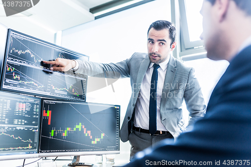 Image of Stock brokers looking at computer screens, trading online.