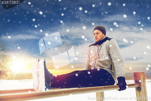 Image of young man exercising on parallel bars in winter