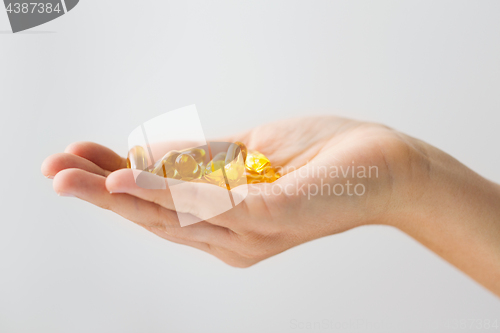 Image of hand holding cod liver oil capsules