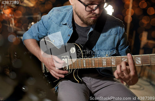 Image of man playing guitar at studio or concert 