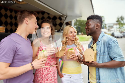 Image of happy friends with drinks eating at food truck