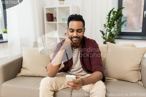 Image of happy man with smartphone at home