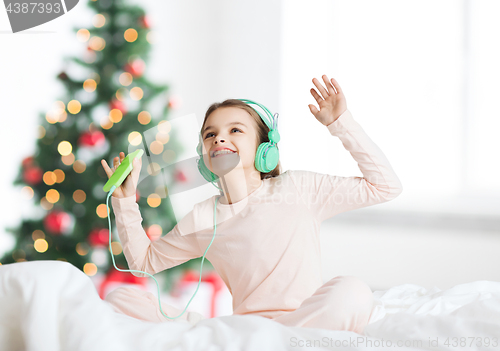 Image of girl with smartphone and headphones at christmas