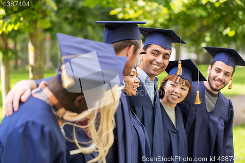 Image of happy students or bachelors in mortar boards