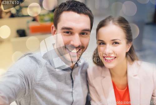 Image of happy couple taking selfie in mall or office