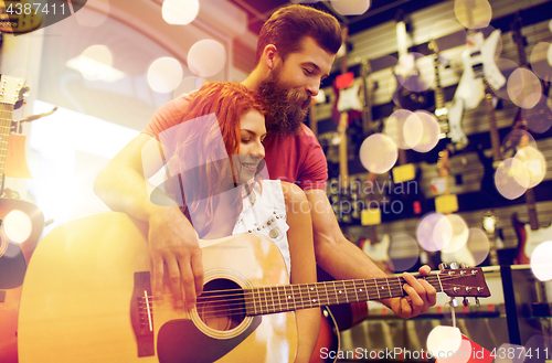 Image of couple of musicians with guitar at music store
