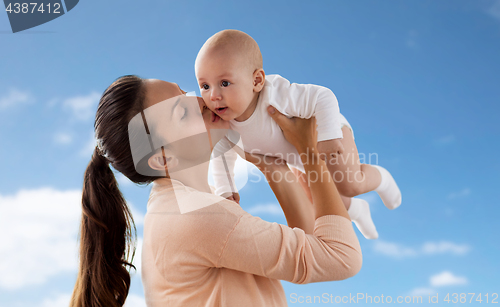 Image of happy mother kissing little baby boy over sky