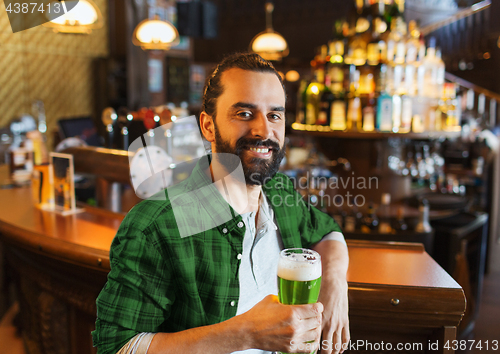 Image of happy man drinking green beer at bar or pub