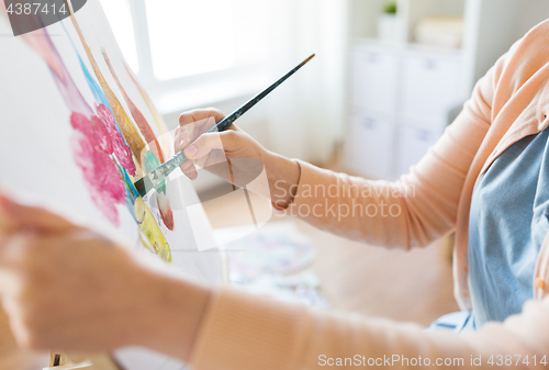 Image of artist with brush painting still life at studio