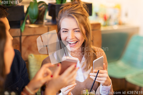 Image of woman with smartphone and friends at restaurant