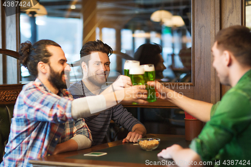 Image of male friends drinking green beer at bar or pub