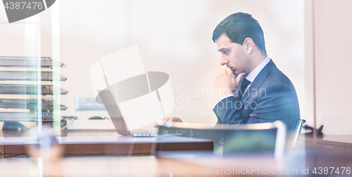 Image of Businessman in office working on laptop computer.