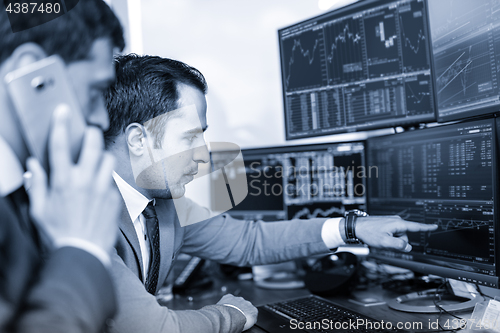 Image of Stock brokers trading online in corporate office.