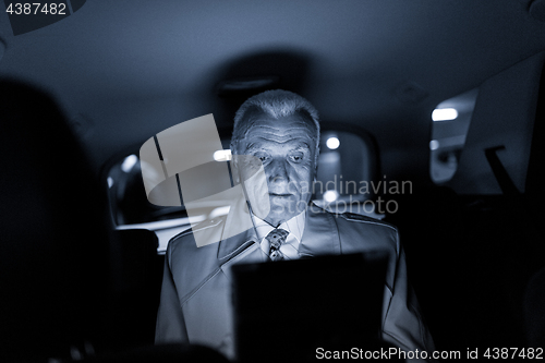 Image of Businessman with a digital tablet sitting in the back seat of a car