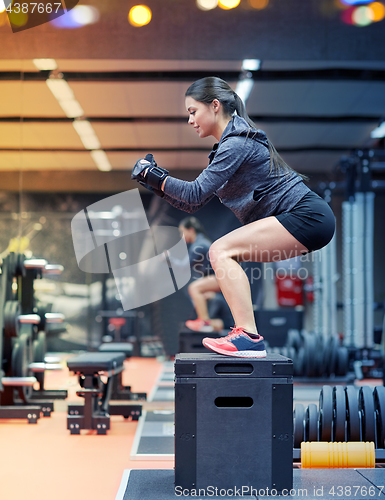 Image of woman doing squats on pnatfom in gym