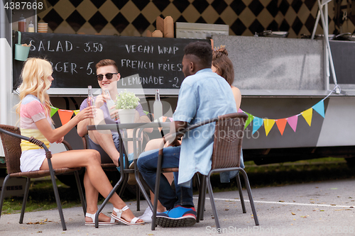 Image of friends with drinks sitting at table at food truck