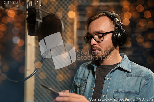 Image of singer with headphones at music recording studio