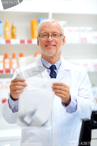 Image of senior apothecary at pharmacy cash register
