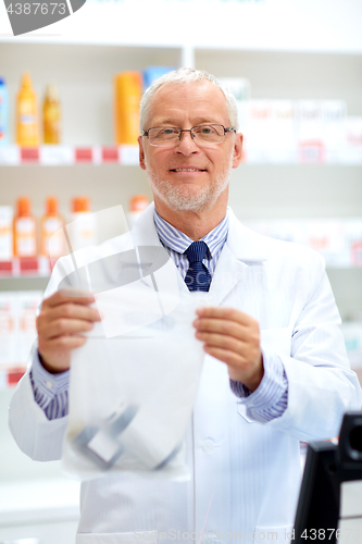 Image of senior apothecary at pharmacy cash register