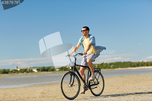 Image of happy man riding bicycle along summer beach