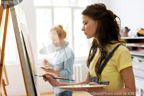 Image of woman with easel painting at art school studio